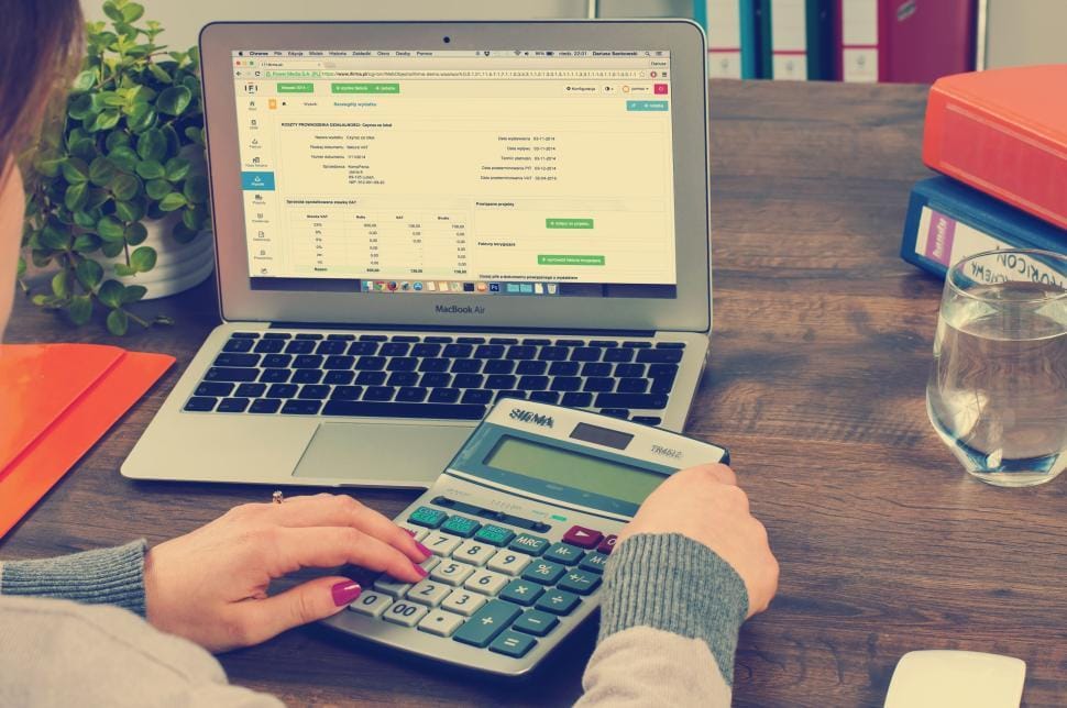 A small business owner reviewing invoices and using a calculator at a desk